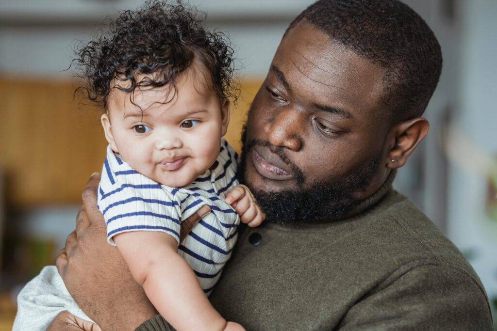 A caring father embraces his curious baby at home, capturing a tender moment of parenthood.